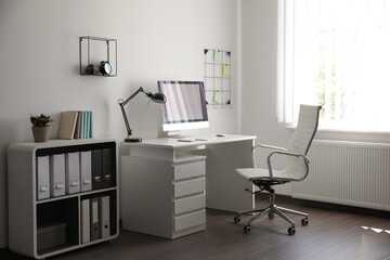 Comfortable white chair near desk in stylish office interior