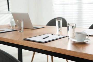 Conference room interior with glasses of water and clipboard on wooden table