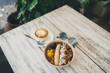 Delicious breakfast bowl and cappuccino on table