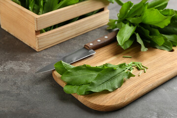 Fresh cut sorrel leaves and knife on grey table