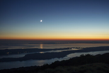 Moon setting above islands in Adriatic sea, view from the top of Velebit mountains.