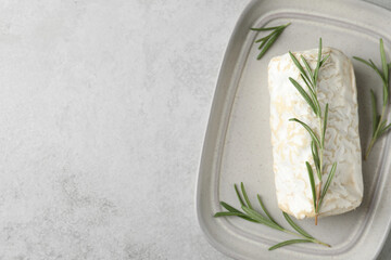 Delicious fresh goat cheese with rosemary on light grey table, top view. Space for text