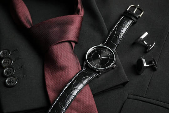 Luxury wrist watch, tie and cufflinks on black jacket, closeup