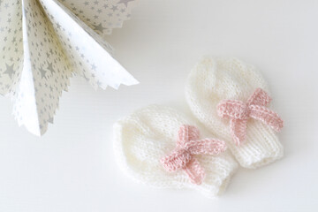 Fototapeta na wymiar knitted white mittens with pink bow