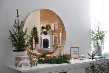 Mirror over chest of drawers with Christmas decor in room. Interior design