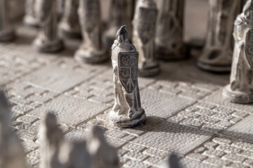 A portrait of a stone soldier as a pawn on a chessboard. The chess game is about to start. The strategic duel between the white and black army.
