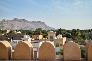 View of Nizwa from inside Nizwa Fort. In the background, there are mountains and a blue sky. Nizwa, Oman.