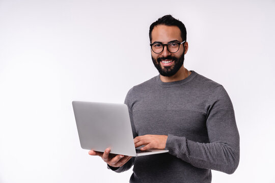 Happy confident young Middle East man using laptop isolated over white background