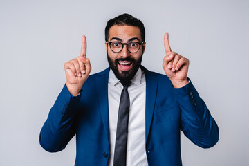 Excited 25s Arabian businessman pointing at copy space isolated over grey background