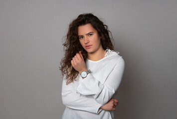 Beautiful young woman with curly hair posing with wrist watch