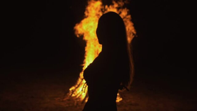 Silhouette of mystic woman in black background of fire fly flame, spark, of contour outline. Adult sexy of young girl witchcraft ceremony ritual dance in underclothes. Outdoor slow motion. Caucasian.