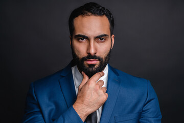 Serious successful arab businessman in formal outfit isolated over black background