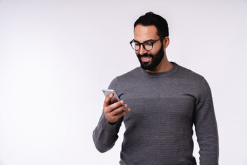 Nice-looking young Arabian man in casual clothes using mobile phone isolated over white background