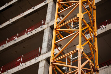Fototapeta premium Yellow construction crane attached to the wall of an office building under construction
