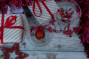 two martini glasses surrounded by new year gifts with red christmas decorations on a blue wooden table. High quality photo