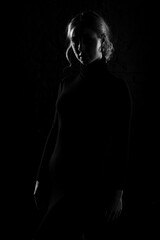 Black and white silhouette of a beautiful woman on a dark background.