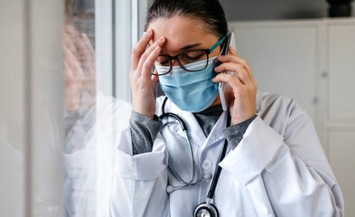 Sad and worried female doctor talking on the phone