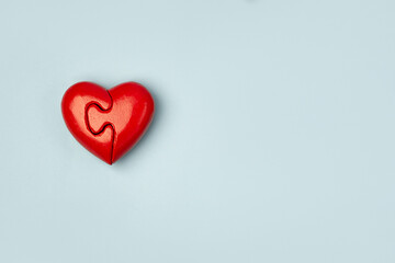 Red heart of two folded halves  on a blue background with copy space . Psychology and Valentine day  concept .