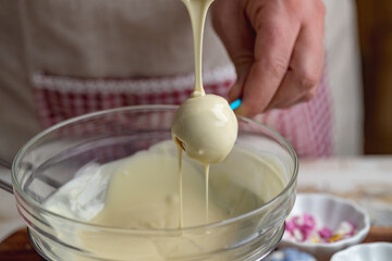 the making of cake pops with a melted chocolate coating