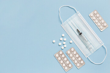 Medical face mask, packaging with pills, expendable syringe for vaccination. Coronavirus vaccination concept.