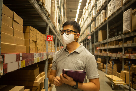 Asian Warehouse Manager Wearing Mask And Check Stock With Tablet For Check Stock.T