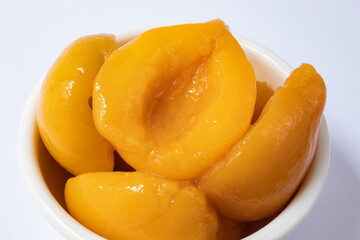 Halved peaches in syrup in white bowl