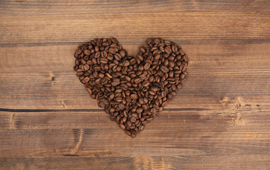 coffee with roasted raw coffee beans making a heart shape on wooden background.
