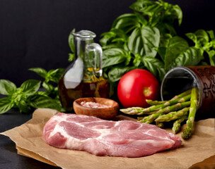 Meat on the black stone with tomato, basil leaves, salt, asparagus and olive oil. Meat steak with spices.