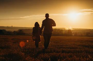 Fototapeta na wymiar A happy couple in a field in the rays of the setting sun