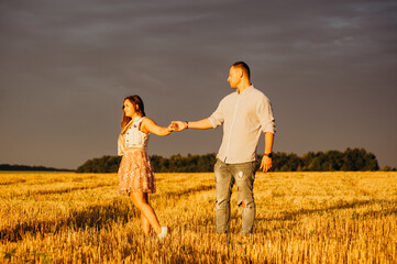 A happy couple in a field in the rays of the setting sun