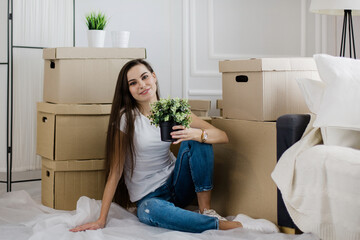 young woman with a home plant sitting on the floor in the new l