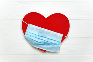 Red heart with blue disposable protective mask on white background. Valentines Day in new normal...