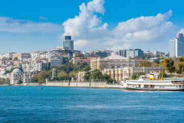 Dolmabahce Palace in the Bosphorus strait in Istanbul Turkey from ferry on a sunny day with background of cloudy sky