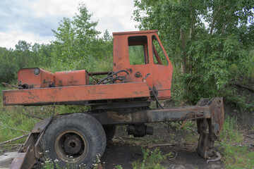 Old skeleton of a truck crane. Frame with wheels and cab. Profile view. Green Forest.