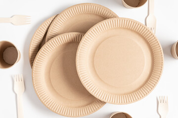 Eco friendly disposable tableware. Wooden forks and paper cups with plates on white background. Eco waste. Flat lay, top view, copy space