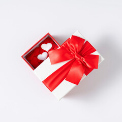 Valentines day background. White gift box with red bow, red hearts on white background. Valentine day concept, design. Flat lay, top view, copy space
