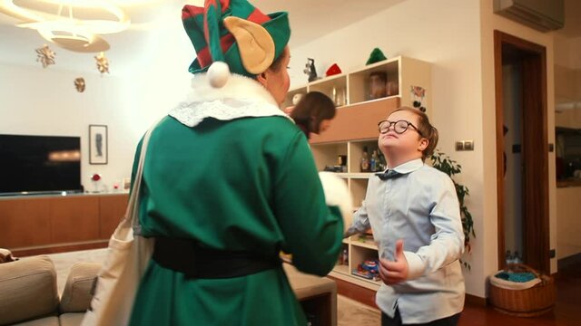 Children play with an actor dressed as a gnome at home. A child with down syndrome talks, treats him to cookies. Interaction in free play.