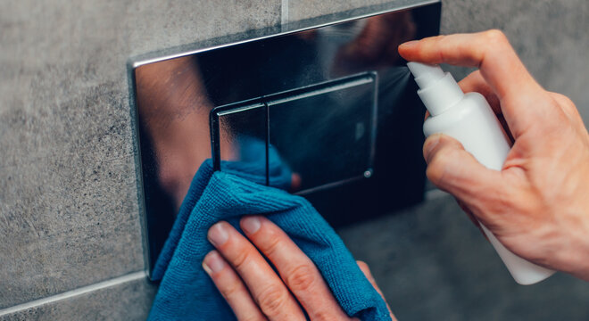 close up. man spraying an antibacterial spray on a wall switch.