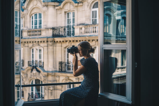 Woman overlooking Paris in Window with camera