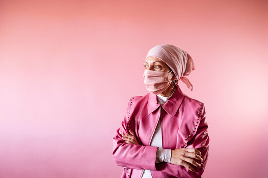Woman with headscarf and pink mask, cancer patient.