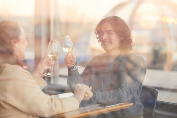 Young couple sitting at the table in the restaurant with glasses of champagne and celebrating their anniversary