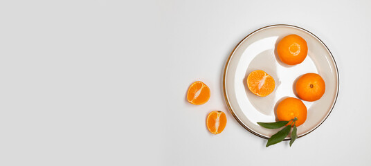 Fresh tangerine or clementin fruits on a beige plate with a gold rim on the table. Colorful fruit background. Flat lay, top view, copy space. Decorative christmas holiday composition