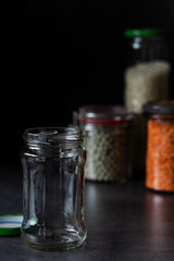 Leeres durchsichtiges Glas steht vor gefüllten Einmachgläsern 