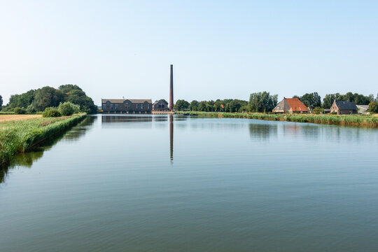 Steam pumping station with long pipe, reflecting in windless canal, Woudagemaal in Lemmer, Friesland, UNESCO World Heritage