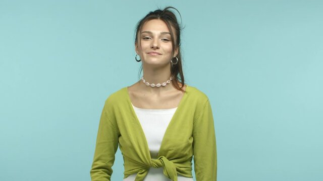 Slow motion of stylish young woman looking confident, smiling assured and showing okay sign, guarantee quality, make no problem gesture, everything good, standing over blue background