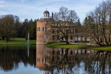 Fototapeta na wymiar Tower and mansion of Rosendael castle with barren winter trees in front reflecting in the still water of the garden pond in the foreground