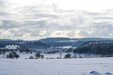 Beautiful winter landscape in Southern Germany showing snow covered meadows and mountain ranges in the background.