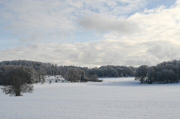 Beautiful winter landscape in Southern Germany showing snow covered meadows and mountain ranges in the background.