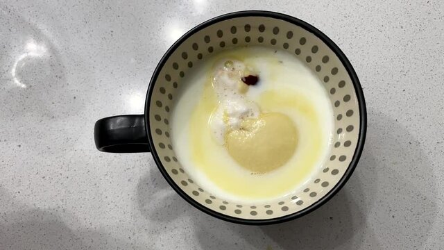 Hot chocolate bomb. Frosty the snowman melts into a cup of hot milk. Child stirring cup. Time lapse.