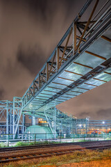 Night scene with pipeline overpass at petrochemical production plant, port of Antwerp, Belgium.